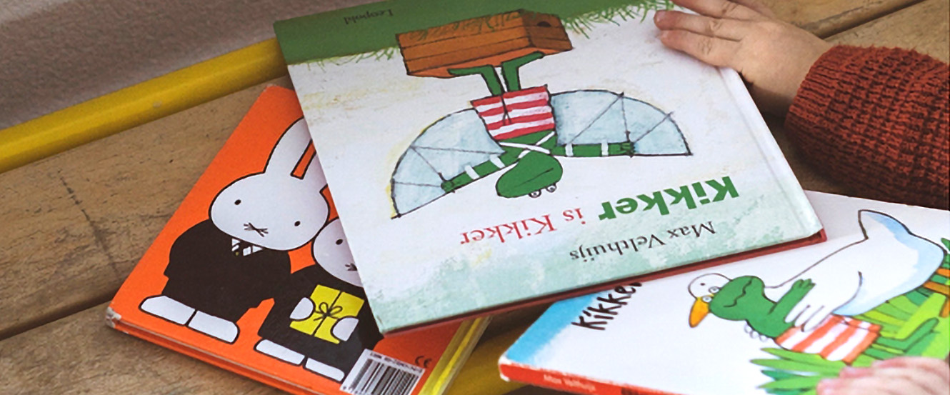 Three childrens books on a bench